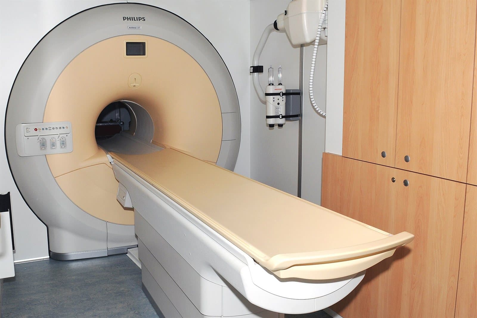 An MRI scanner installed in a medical facility, its circular bore facing an empty patient table.