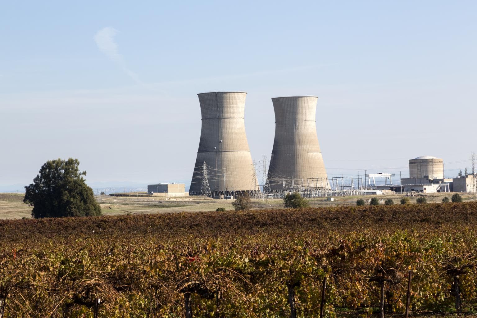 Two large hyperbolic cooling towers standing side by side under a clear sky.