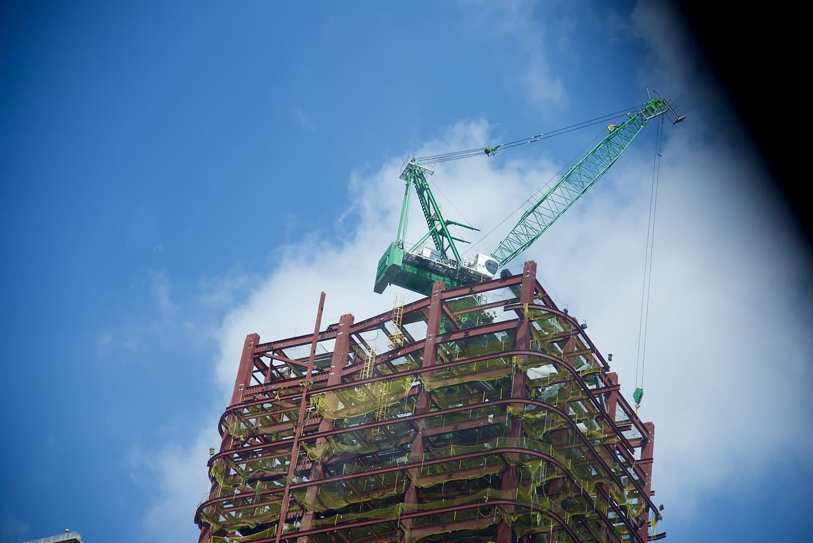 The bare steel frame of a building under construction, columns and beams bolted into a grid against the sky.